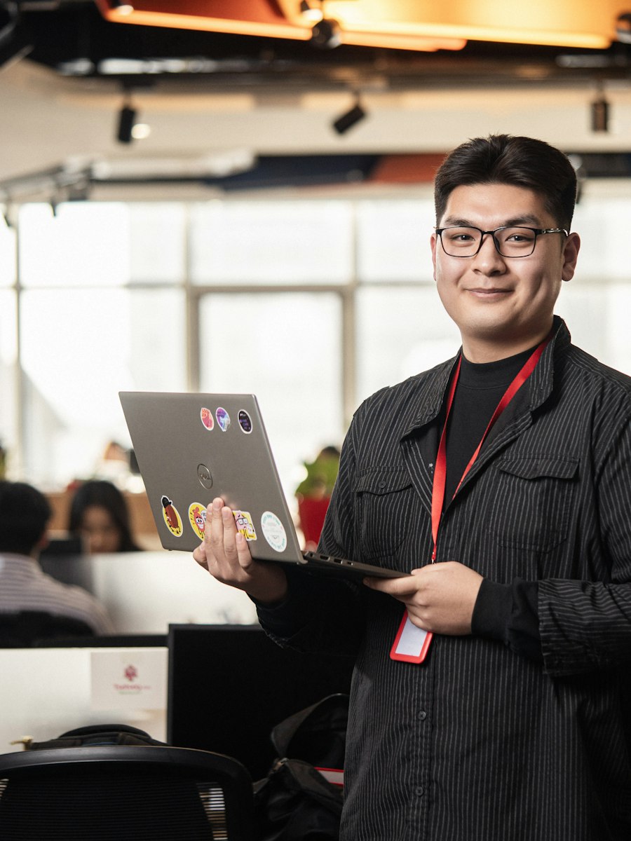 Southeast Asian professional holding a laptop at work